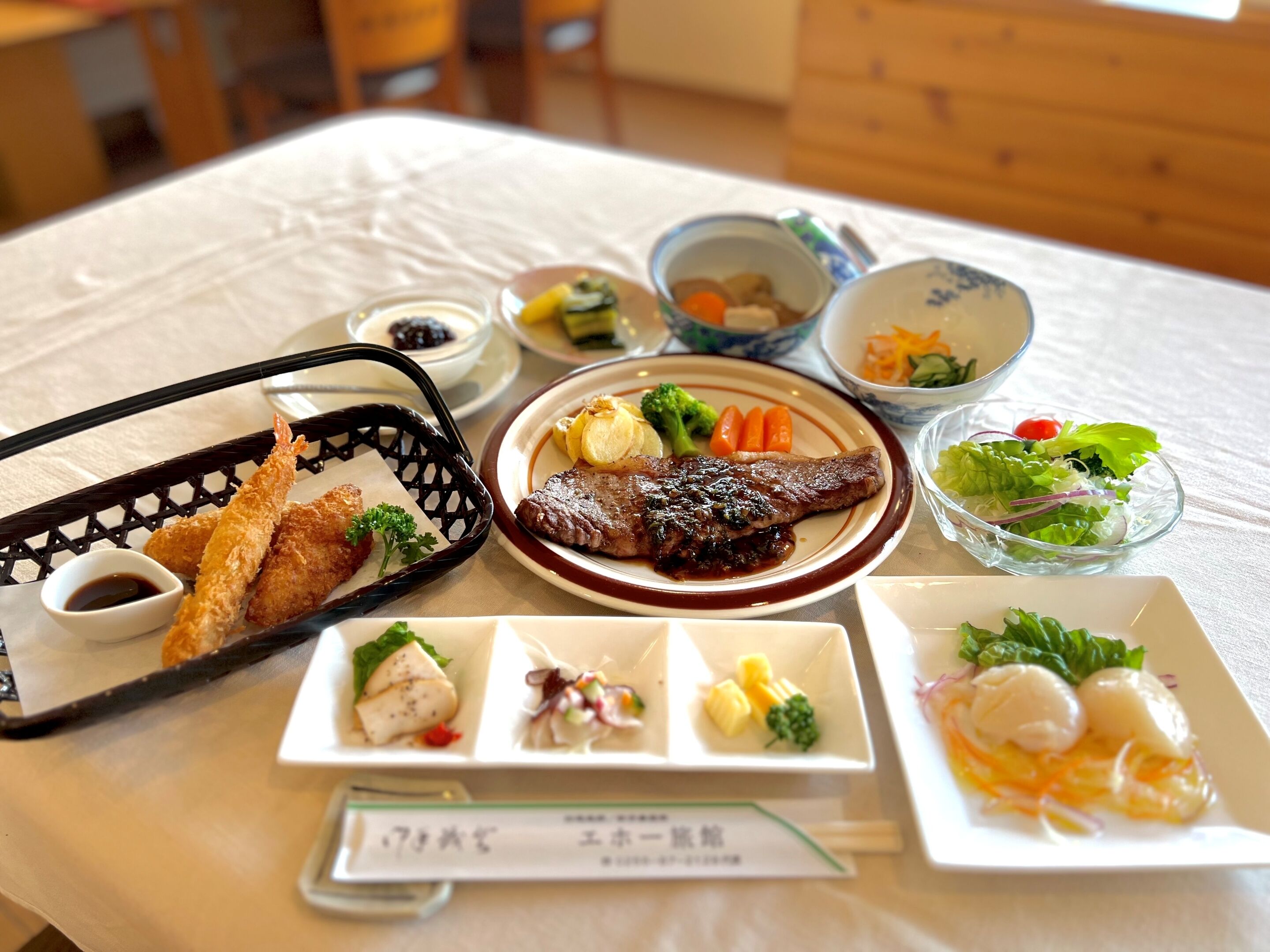 A table with various dishes including a steak, vegetables, and a salad.