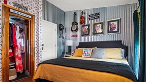 Ein Schlafzimmer mit Bett, Kleiderschrank und Spiegel. An den Wänden hängen Bilder in Rahmen, und ein Nachtlicht steht auf dem Nachttisch.