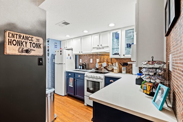 A modern kitchen with white cabinets, a stove, and a sink. There's a sign on the wall that reads "Entrance to Honky Tonk."