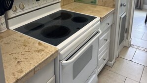 Una cocina con armarios blancos, microondas, estufa y salpicadero de azulejos.