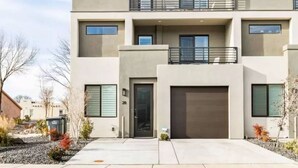 A modern multi-story residential building with a flat roof, large windows, and a garage.
