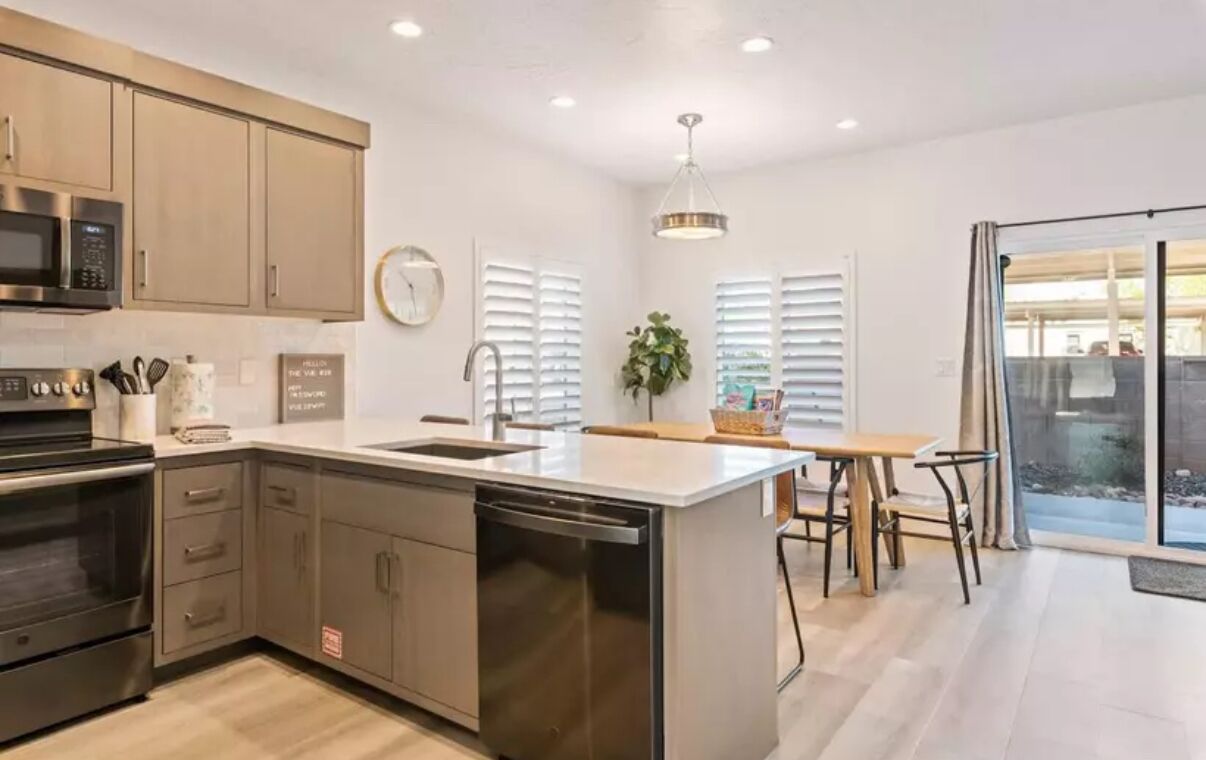 A modern kitchen with stainless steel appliances, a central island, and a dining area with a view.