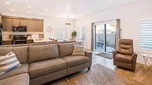 A modern living room with a sofa, a recliner, and a dining area with a table and chairs.