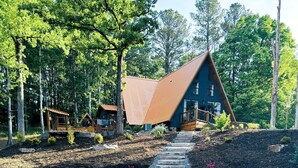 Un chalet rustique, accessible par un sentier de pierres, et entouré d’arbres.