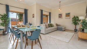 A modern living room with a dining area, featuring a sofa set, a dining table with chairs, and a coffee table.