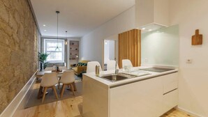 A modern kitchen with a central island, white cabinetry, and a stone accent wall.