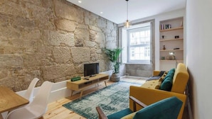 A living room with a stone wall, a television, a sofa, and a dining area.