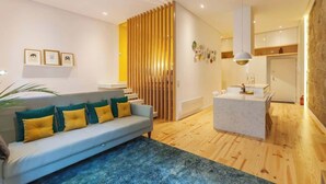 A modern living room with a sofa, a coffee table, and a kitchen area in the background.