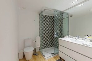 A modern bathroom with a glass-enclosed shower, a white toilet, and a vanity with a mirror. - Historic Stone Charm Apartments by HostWise (Porto)