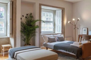 A bedroom with a bed, a chair, a desk, a potted plant, and a window. - Historic Stone Charm Apartments by HostWise (Porto)