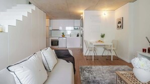 A modern living space with a white sofa, a dining table, and a kitchen in the background. - Modern 4-Apt Retreat for 14, Porto by HostWise (Porto)