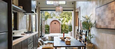 A modern kitchen with a dining area, featuring a large window, built-in cabinets, and a dining table with chairs.