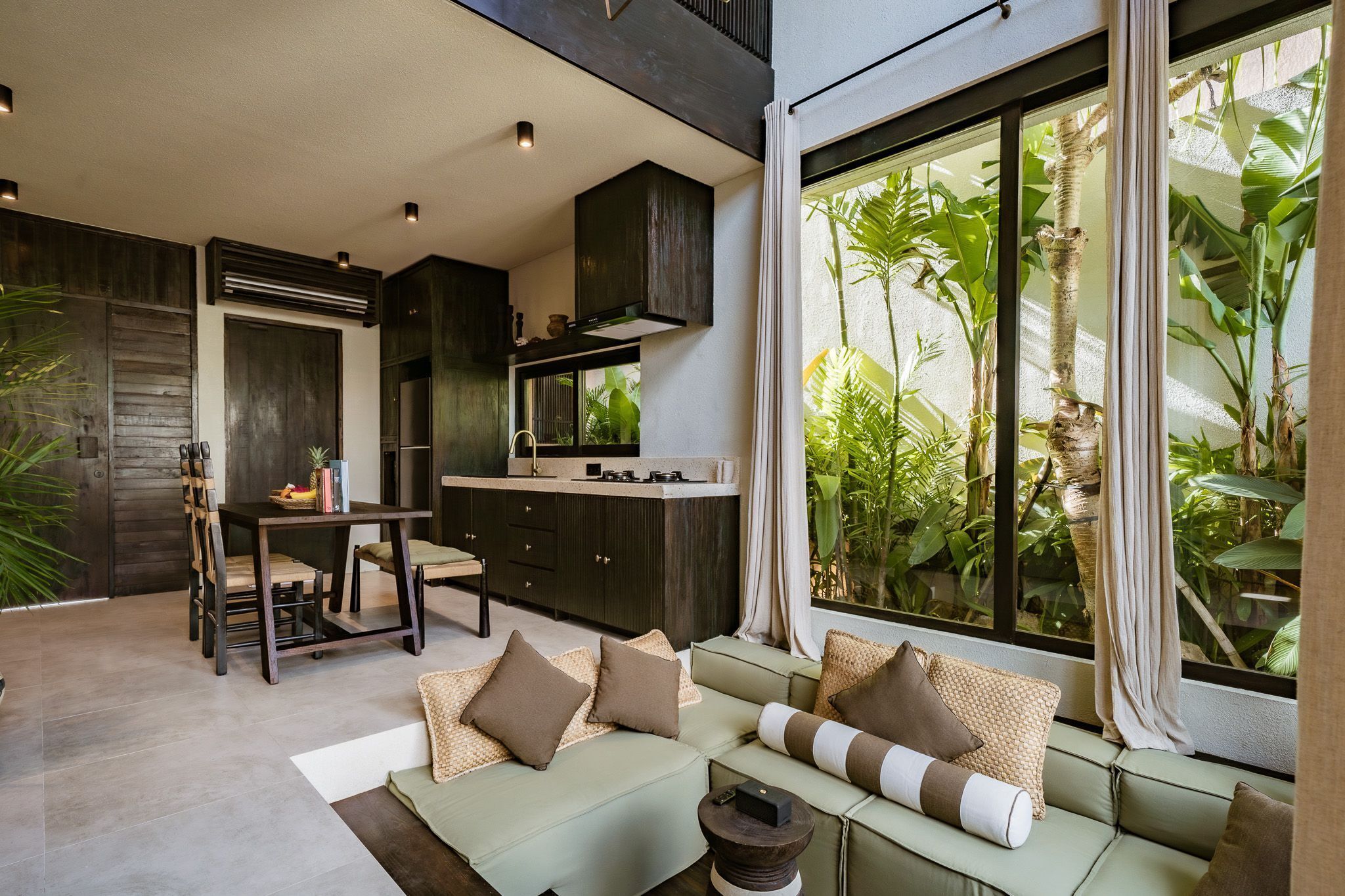 A modern kitchen with dark cabinetry and a dining area with a table and chairs.