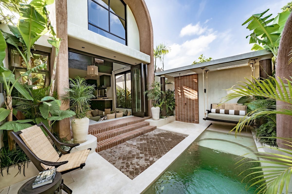 Une maison moderne dotée d’une piscine, d’un espace de détente extérieur et d’une végétation luxuriante.