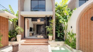 A modern building with a brick facade, large windows, and a pool area with steps leading to the entrance. - Bedouin Loft Pererenan (Canggu)