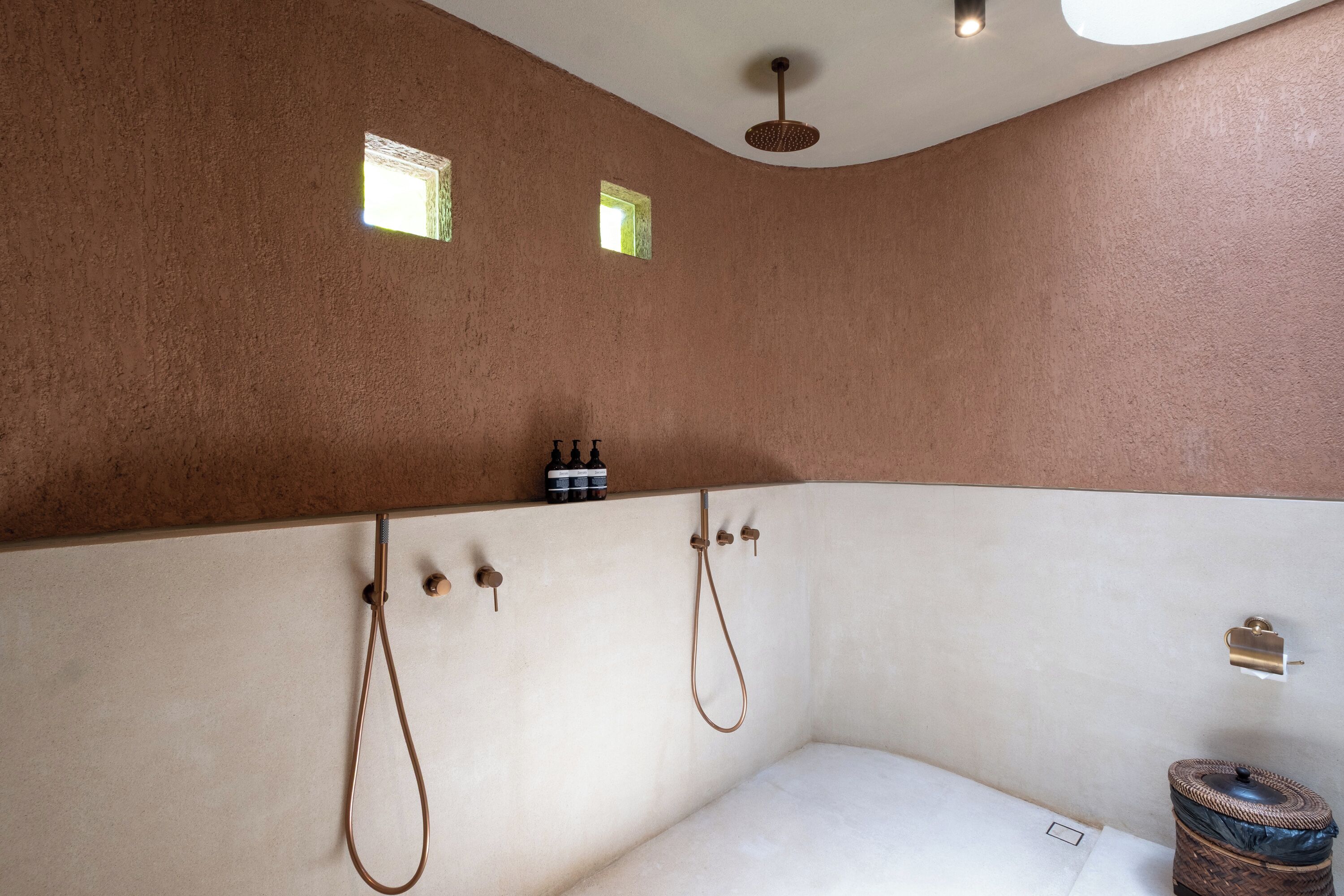 A bathroom with a bathtub, two showerheads, and a ceiling light fixture.
