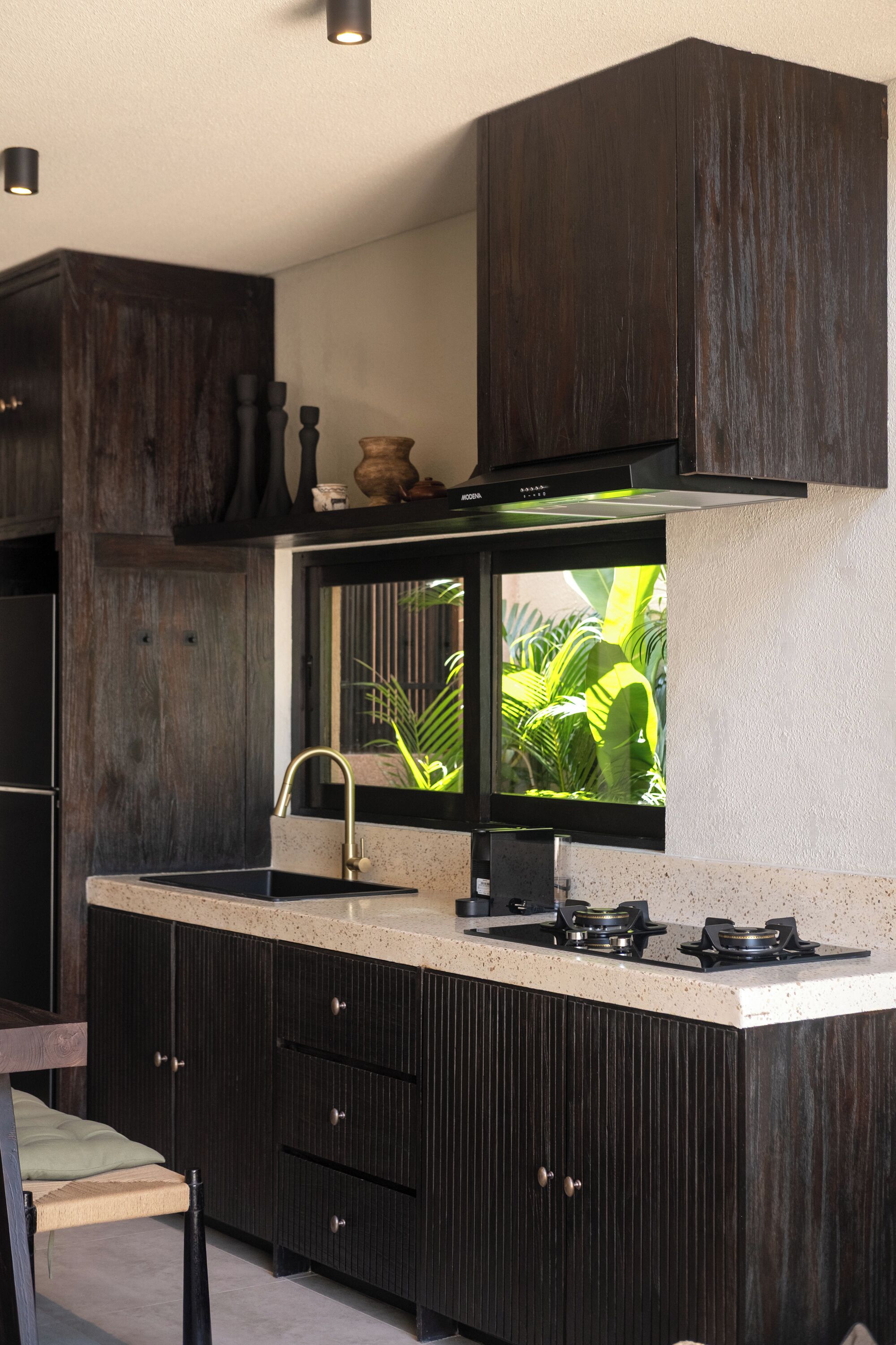 Una cocina moderna con armarios de madera oscura, un lavamanos de acero inoxidable y una ventana con vistas a zonas verdes.