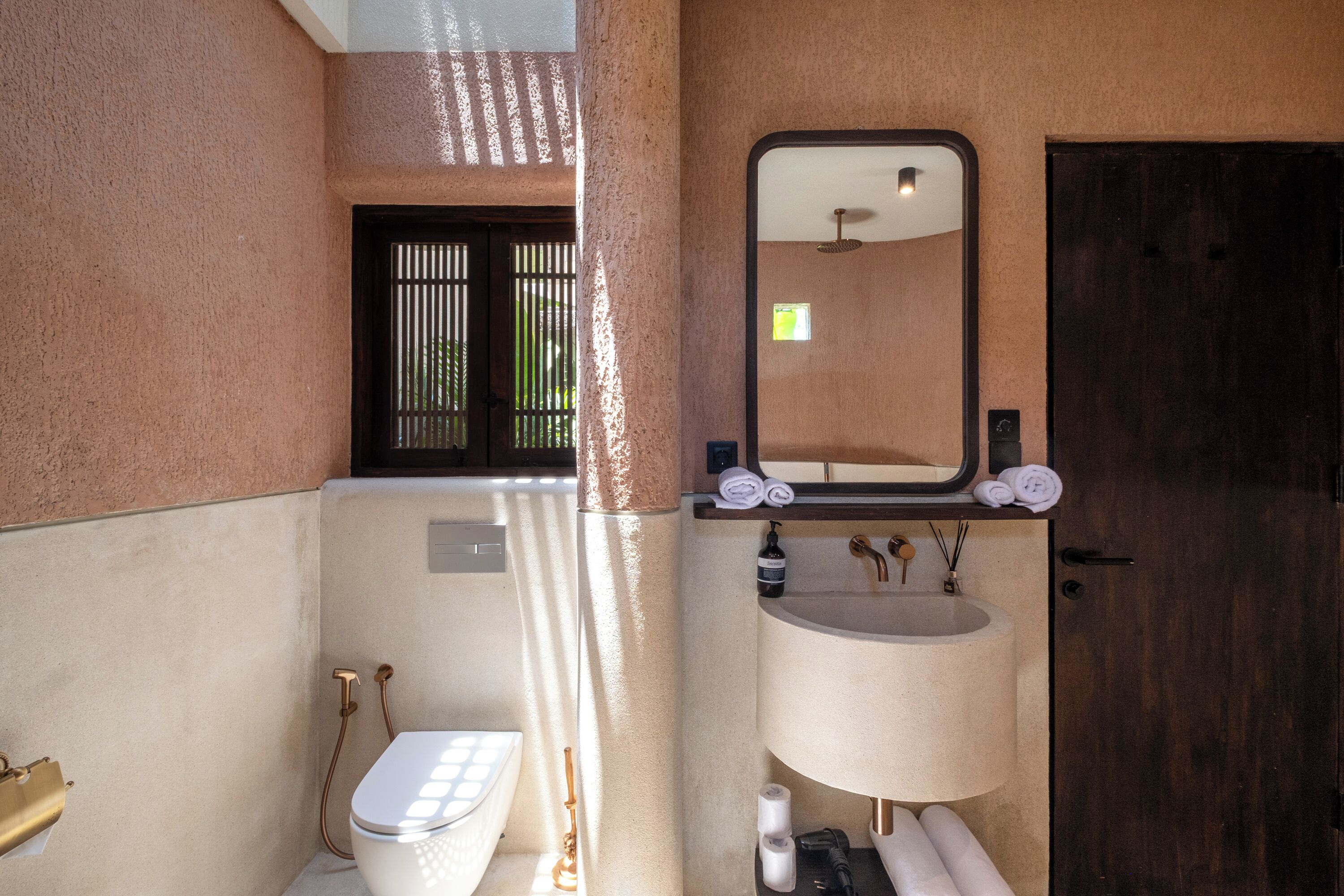 A bathroom with a toilet, sink, and mirror.