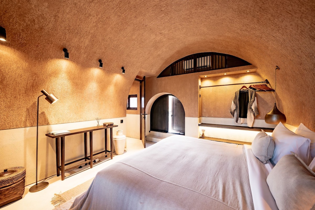 Une chambre à coucher avec un grand lit, une table de chevet, un miroir et une armoire.
