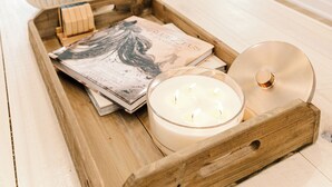 Una habitación acogedora con una bandeja de madera que contiene una vela, un libro y un objeto decorativo.