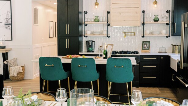 Una cocina moderna con armarios oscuros, una encimera blanca y sillas verdes.