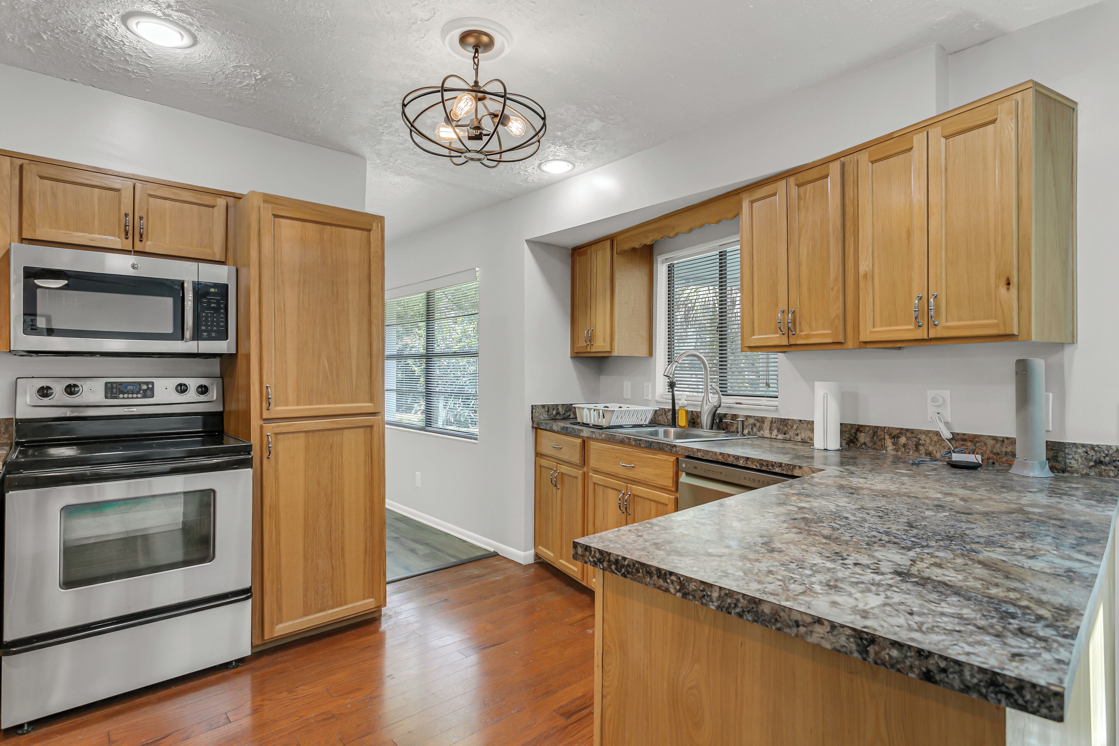 A kitchen with wooden cabinets, a stainless steel oven, a microwave, and granite countertops.