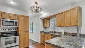A kitchen with wooden cabinets, a stainless steel oven, a microwave, and granite countertops.