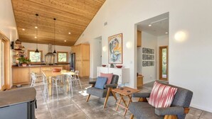 A spacious living area with a high ceiling, a dining table with chairs, a sofa, and a coffee table.
