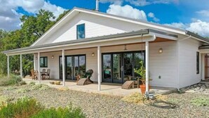 A modern house with a covered patio, large sliding glass doors, and a chimney.