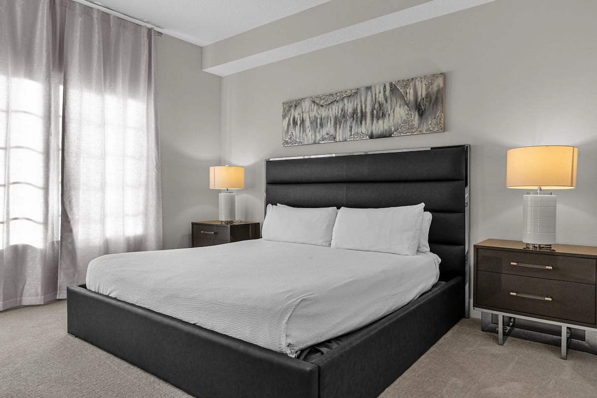 Una camera da letto moderna con un letto grande, due comodini e una testiera.