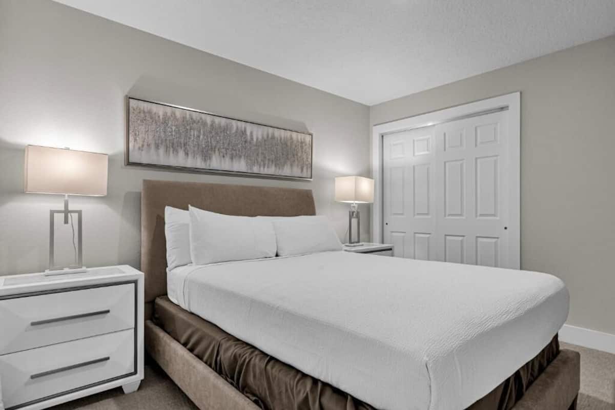 Una camera da letto ordinata con un letto grande, due comodini con lampade, una testiera e una porta.