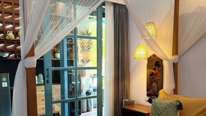 A room with a bed, a nightstand, a lamp, and a window with curtains. - Omah Dingoto (Sewon)