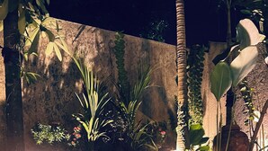 A swimming pool with clear blue water, surrounded by plants and a stone wall. - Omah Dingoto (Sewon)