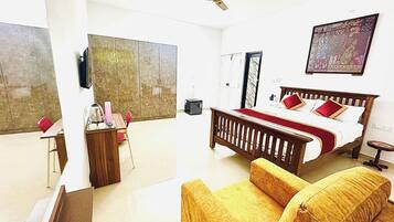 Quarto de hotel com cama, sofá, escrivaninha e cadeira.