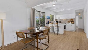 Una cocina moderna con armarios blancos, una isla central y taburetes de bar.