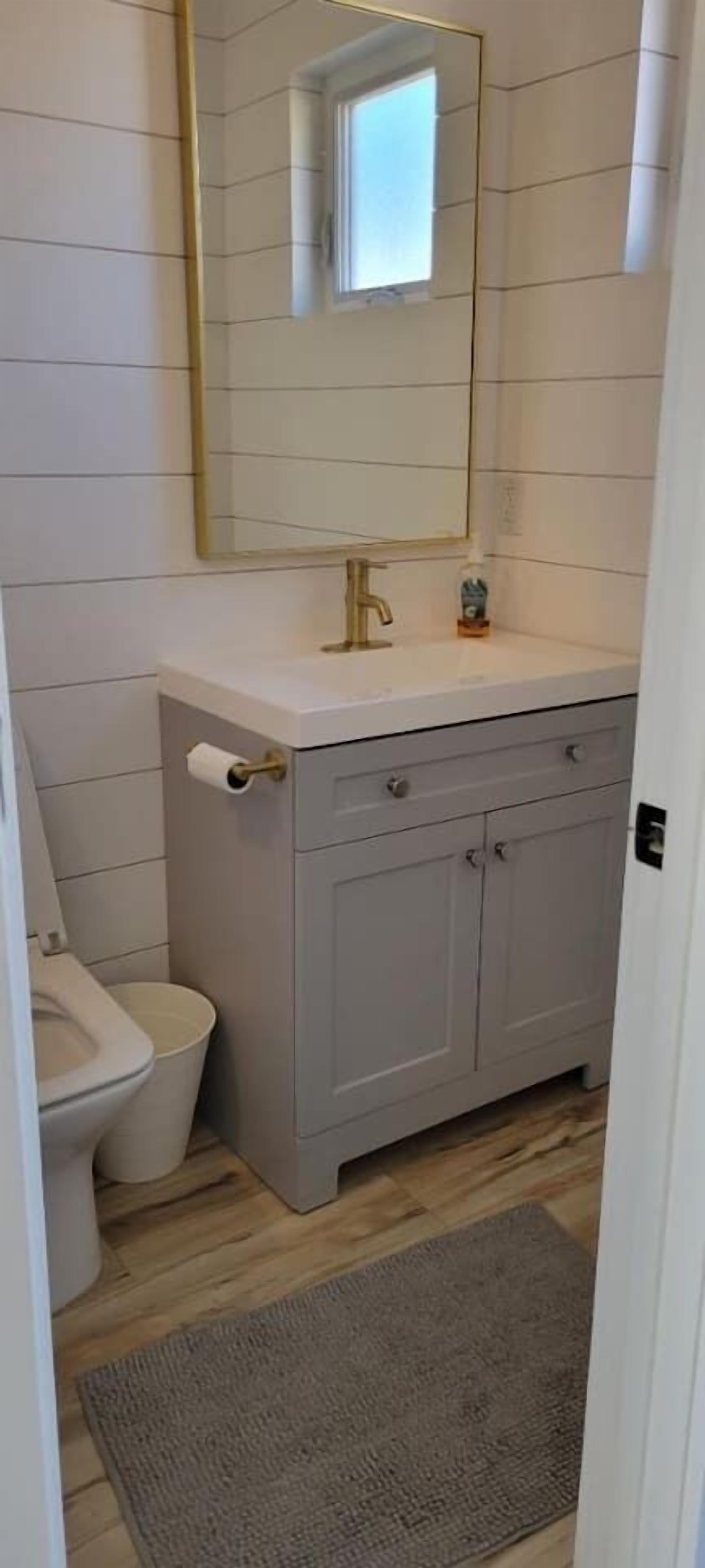 Une salle de bain avec des toilettes, un lavabo et un miroir.
