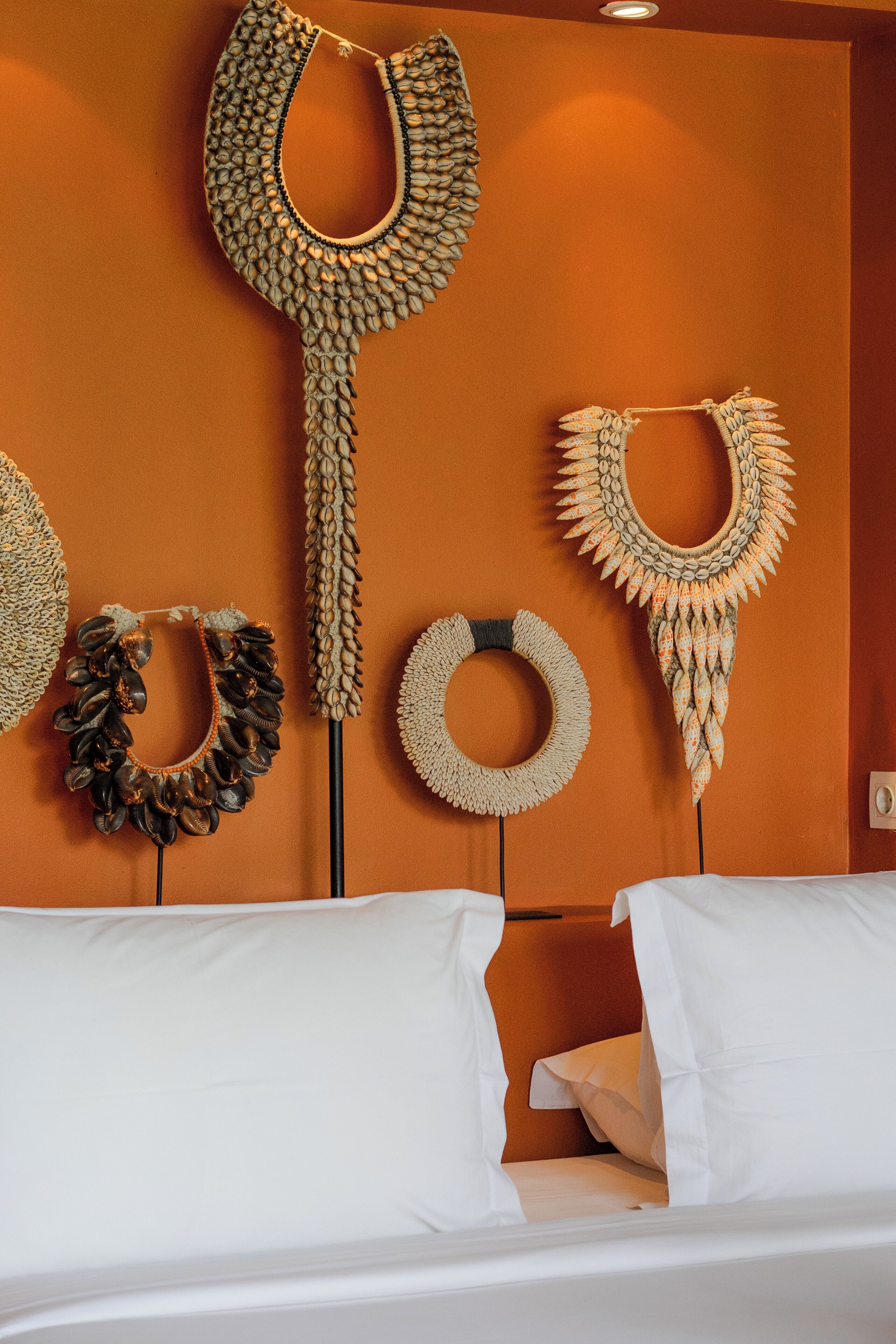 Un letto con lenzuola bianche e una testiera, una parete con quattro decorazioni murali e una porta in legno.