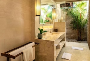 A modern bathroom with a large mirror, a sink, and a towel rack. - Villa Tigapuluh (Seminyak)
