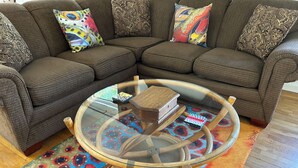 A brown sectional sofa with patterned cushions, a glass coffee table with wooden legs, and a colorful rug. - Wolf Creek Basecamp - Premier fishing! Walking distance to restaurants and bars (Wolf Creek)