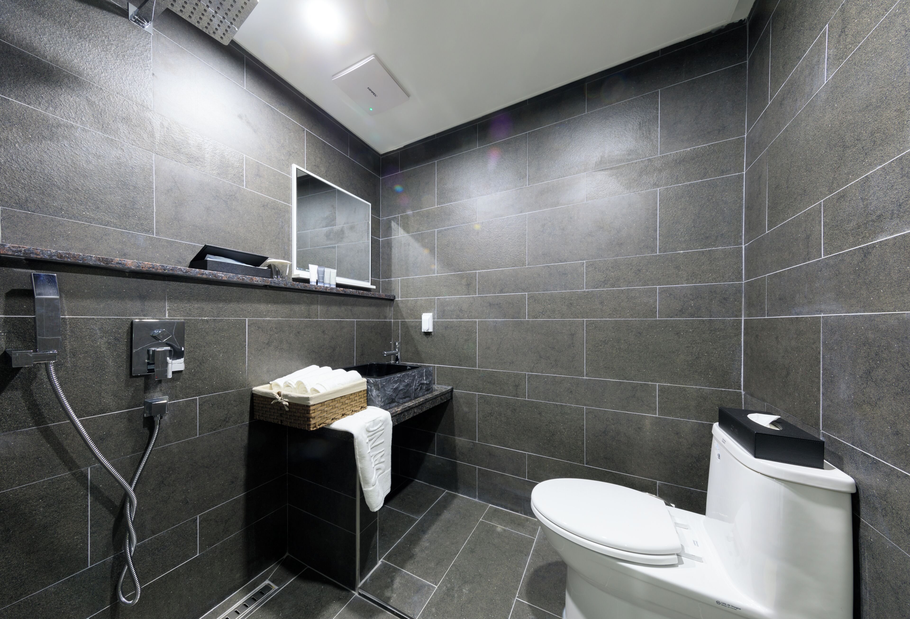 A modern bathroom with a black sink, white toilet, and a shower area.