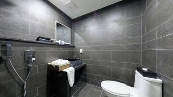 A modern bathroom with a black sink, white toilet, and a shower area.