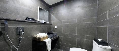Un baño moderno con un lavamanos negro, un inodoro blanco y una zona de ducha.