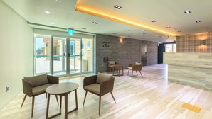 Un hall d’entrée moderne avec des sièges, un comptoir d’accueil et une entrée avec une porte en verre.
