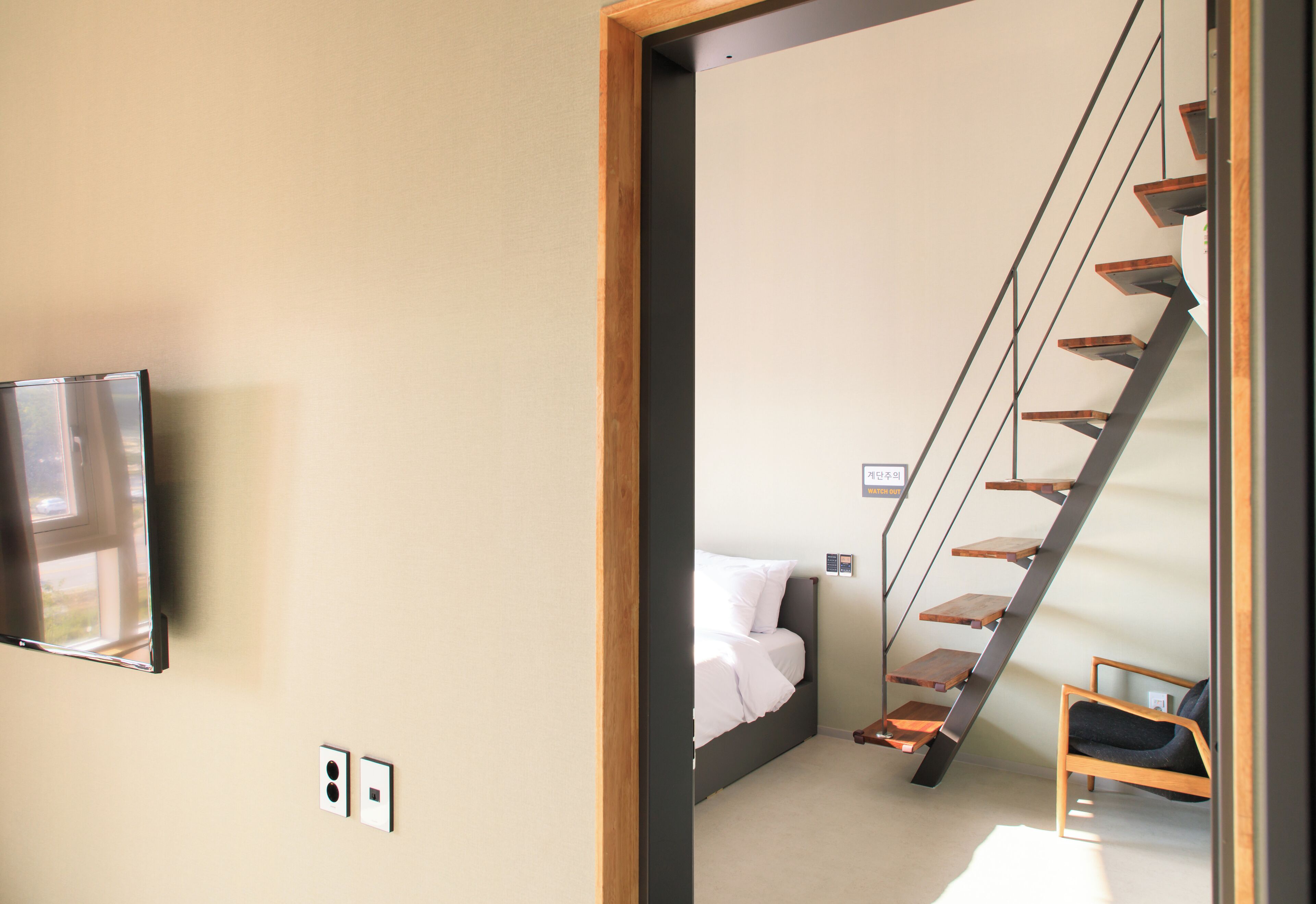 Une chambre d’hôtel avec un lit, une chaise, une télévision et un escalier.