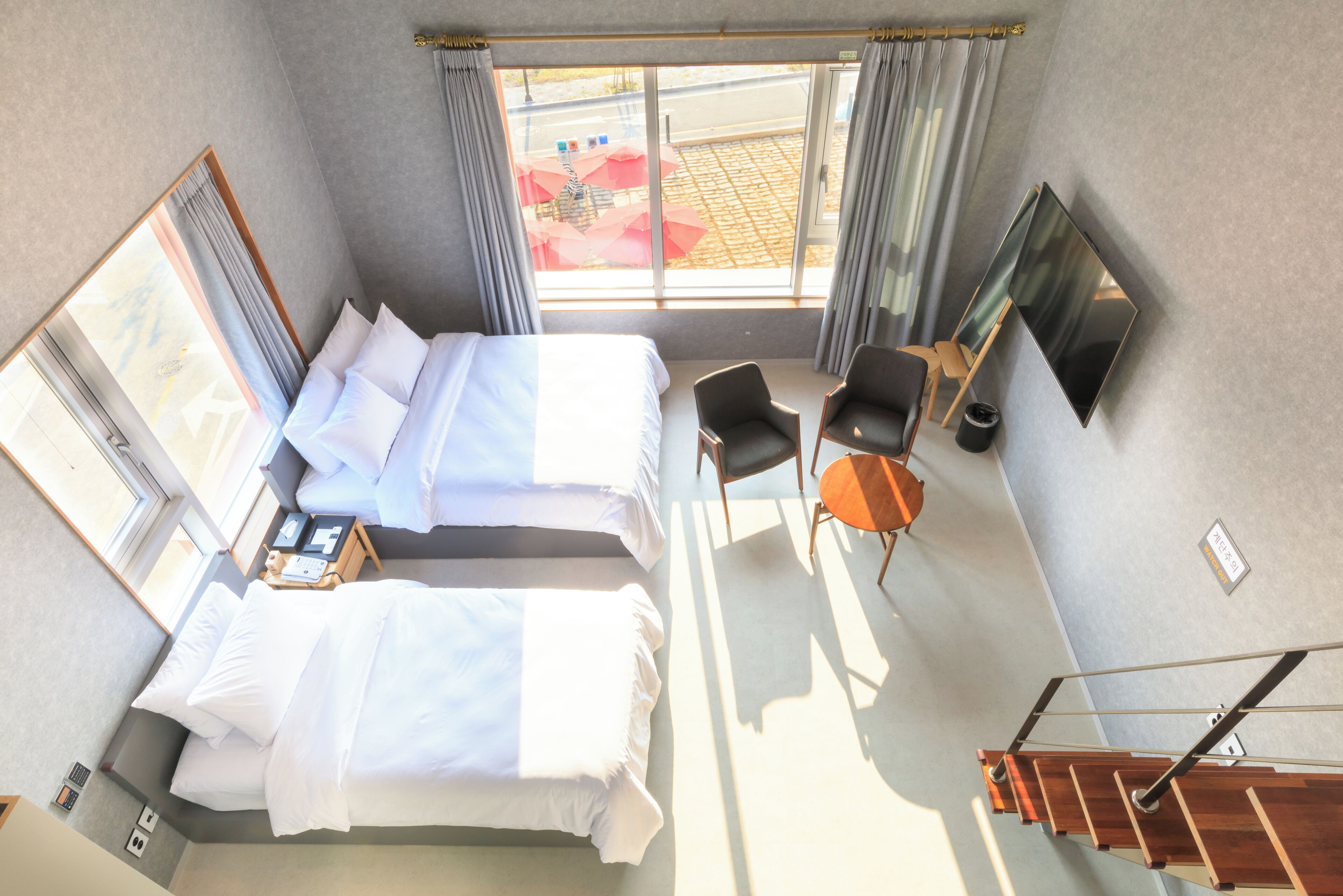 Une chambre d’hôtel avec deux lits, un bureau, une chaise, une télévision et une fenêtre avec des rideaux.