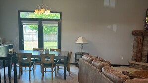 A dining area with a table and chairs, a sofa, a lamp, and a chandelier. - Superb 5-bedroom house in Big Lake in friendly, safe neighborhood. (Big Lake)