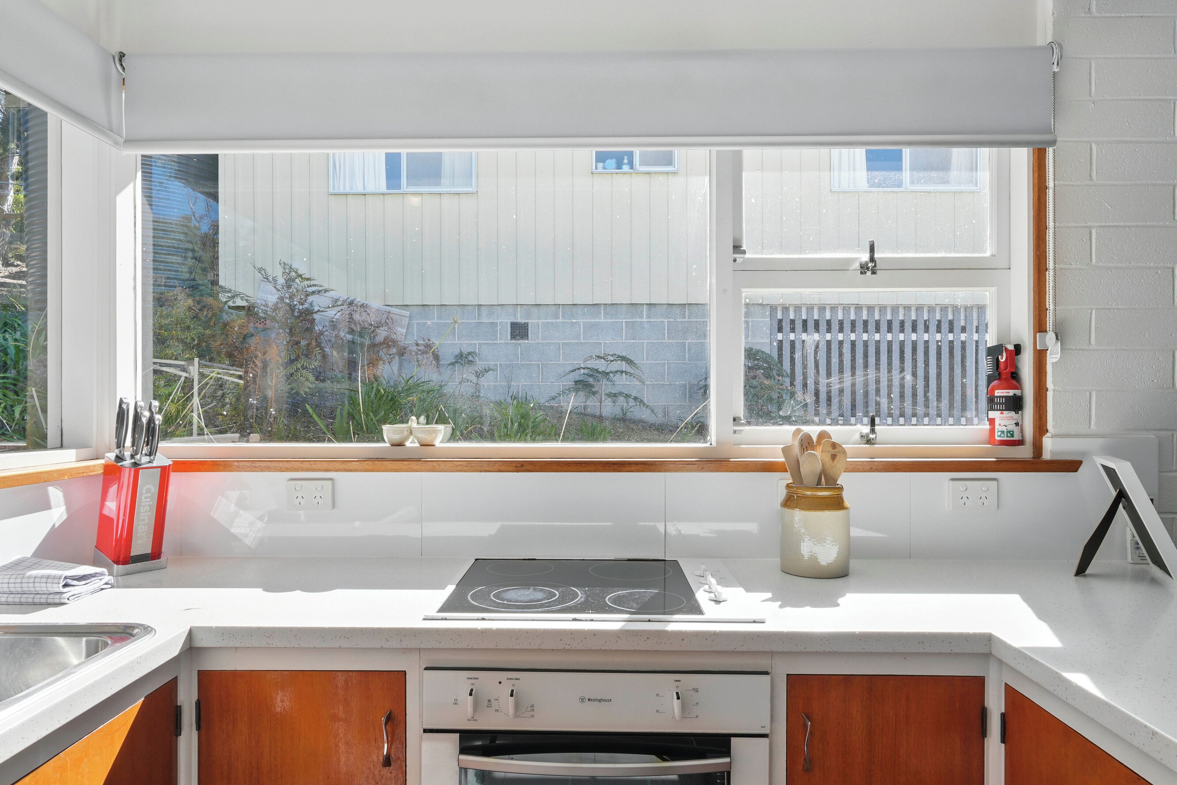 A modern kitchen with a large window, white cabinetry, and a built-in oven.