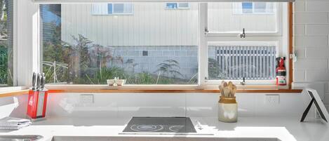 A modern kitchen with a large window, white cabinetry, and a built-in oven.