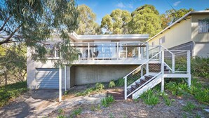 Une maison moderne dotée d’un grand garage, d’un espace extérieur couvert et d’un escalier menant à l’étage supérieur.