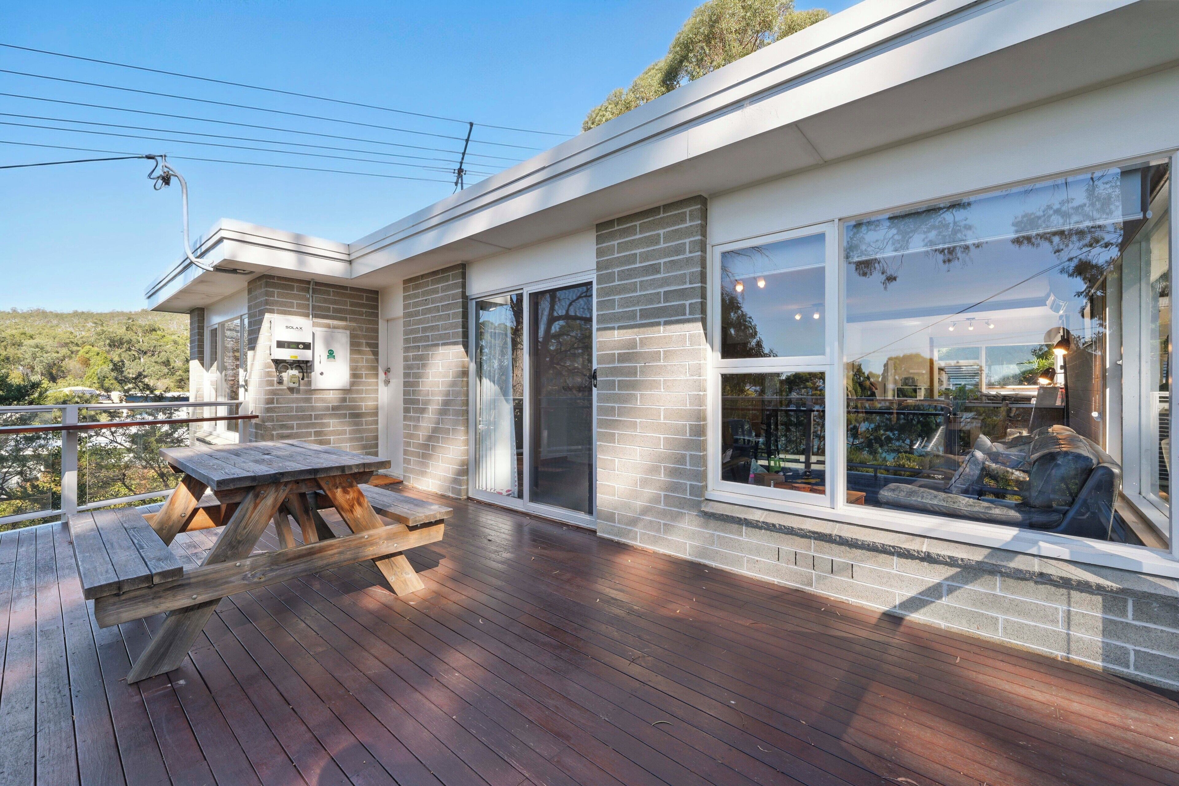 A modern house with a deck, a brick exterior, and large windows.